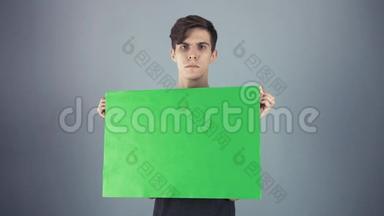 年轻男子身穿黑色衬衫，手持绿色钥匙片<strong>海报</strong>，<strong>灰色背景</strong>
